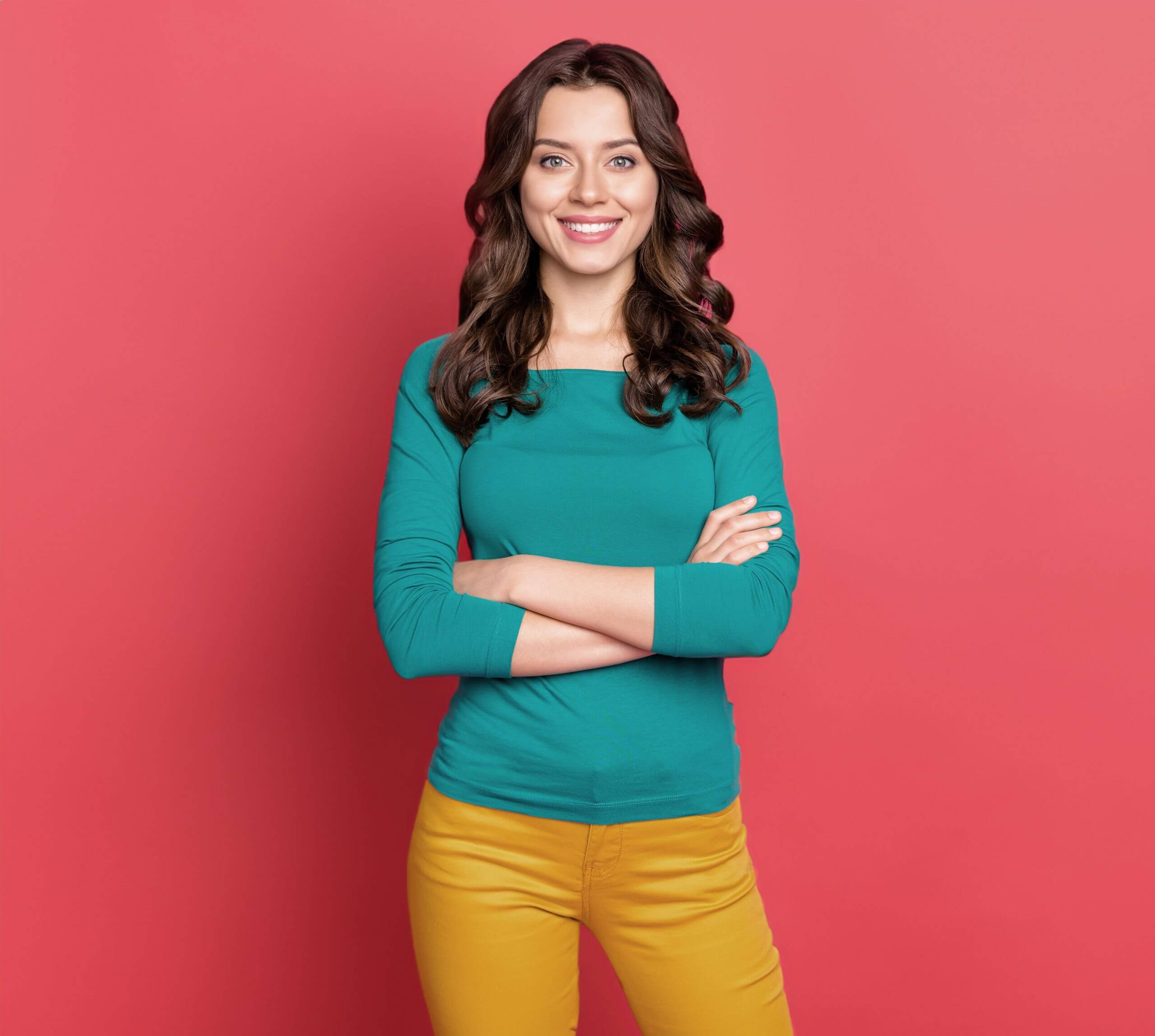 Portrait of smiling woman with her arms crossed in front of a pink background